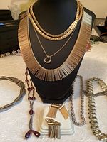 Gold-tone fringe and snake chain necklaces with heart pendant, matching fringe earrings, and chunky silver-tone necklaces including a purple bead chain.