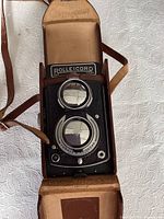 Top view of Rolleicord camera in open brown leather case; shows viewing lens, taking lens and camera body.