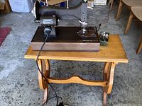 Side view of vintage Singer sewing machine on oak side table showing sewing machine details and base.