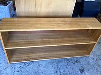 Front view of the wooden bookshelf showing two shelves and wood grain.