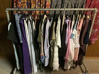 Photo of assorted ladies clothes on hangers showing dresses, tops, pants, skirts in various colors and styles.