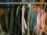 Assorted ladies sweaters and blouses in pastel and dark tones hanging on rack
