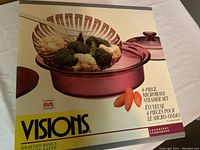 Front of box showing the 4-piece microwave steamer set in cranberry color with vegetables inside