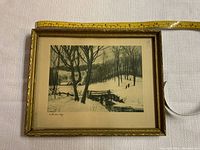 Front view of framed winter landscape print showing scene and frame details with tape measure for size reference.