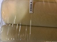 Blanket folded inside clear plastic packaging showing pale yellow color and texture.