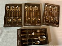 Four boxes containing new silverware sets, with spoons, forks, and knives visible.