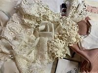 Close-up of assorted cream colored crocheted lace textiles and folded fabric pieces in trunk