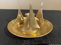 Top view showing three brass sailboats arranged on a round brass base with central candle holder.