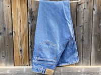 Full folded view of Levi's blue denim jeans hung showing back pocket and part of leg