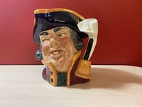 Side view of the Royal Doulton Town Crier Toby Jug showing detailed face and hat with scroll handle.