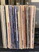 Side view of approximately 38 vinyl record albums tightly packed together on a shelf, showing a variety of spine designs and conditions.