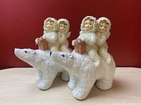 Pair of vintage chalkware ceramic Christmas decorations depicting two angels riding polar bears with gifts.