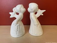 Front view of the two white ceramic angels kissing, showing their wings and detailed dresses.