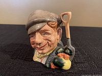 Front view of the ceramic mini jug showing the detailed face of the gardener and the shovel handle with vegetables by Royal Doulton.