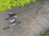Two fishing rods laid on the ground, one with Star Drag spin caster reel and the other with Shimano ML40 spinning reel.