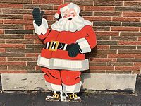 Full front view of Santa Claus cutout leaning against brick wall
