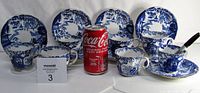 Front view of all 7 Royal Crown Derby cups and their matching saucers, blue and white Mikado pattern, Coca-Cola can for scale.