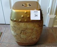 View of the front, highlighting gold top, textured beige body and auction lot number