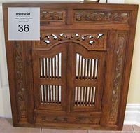 Front view of carved wooden mirror with closed hinged doors
