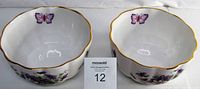 Pair of white bone china bowls with purple wild violet floral design and butterflies inside the bowl rim. Both have thin gold trim edge and two original Aynsley stickers. The bowls measure approximately 4 inches in diameter and 2 inches tall. Clean, bright, excellent condition with no chips or cracks
