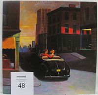 Front cover of the vinyl LP album Crush by Orchestral Manoeuvres In The Dark showing artwork of a city street at dusk and a couple in a convertible car.