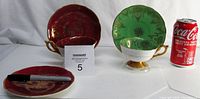 Pair of footed teacups and saucers displayed beside a Coke can for scale, includes green and burgundy sets plus an extra burgundy saucer.