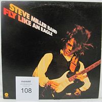 Front cover of Fly Like An Eagle vinyl LP showing Steve Miller Band guitarist in action holding an electric guitar on black background with large text.