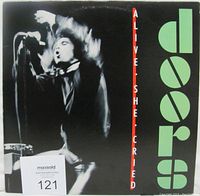 Front cover of The Doors Alive She Cried vinyl LP, showing black and green design with Jim Morrison image and band/album title text.