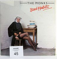 Front view of the vinyl album cover showing a nun sitting in stockings near a wooden table against white brick wall, with the title 'Bad Habits' in red and 'The Monks' printed above.