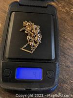 Necklace piled on digital scale showing weight display roughly 4 grams