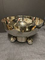 Full view of the metal champagne cooler showing the round bowl and base with spherical feet