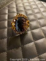 Front angled view of the cameo ring showing the detailed woman's profile on glass and surrounding yellow and clear stones set in a gold-tone metal