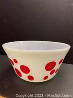 Photo showing side view of white milk glass bowl with large and small red polka dots on exterior surface.