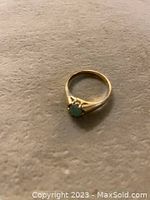 Photo showing the full ring with green jade stone in prong setting on a neutral background.