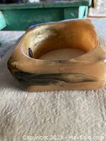 Side view of the honey-colored square lucite bangle bracelet showing smooth surface and marbled color details.