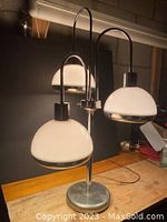 Front view of three-arm lamp showing all white dome-shaped shades with chrome trim, metal arms, and base