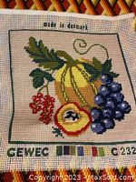 Close-up of hand embroidered pillow case cover with fruit motif, showing detailed stitching and 'made in denmark' label.