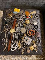Full top view of various jewelry pieces arranged on a black velvet handmade quilted box.