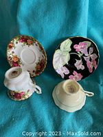 Two tea cups with matching saucers displayed on blue cloth background
