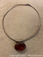 Full view of the sterling silver choker laid flat, showcasing its length and the attached oval amber pendant.