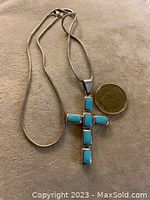 Full view of the vintage sterling silver cross pendant necklace with the pendant and chain laid out next to a coin for scale.