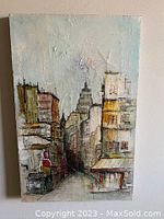 Front view of signed oil on canvas painting showing urban cityscape with buildings and a street in between.