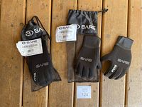 Two pairs of Bare Sports 5mm Pro scuba gloves, one pair showing front and back, laid out with packaging bags on a wooden surface.