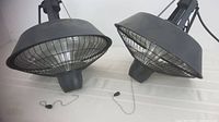 Two hanging electric space heaters shown at an angle highlighting their size and chain length