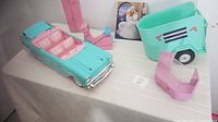Vintage 1980s Barbie turquoise and pink convertible, exercise bike, pink locker, and Barbie holiday card in the background