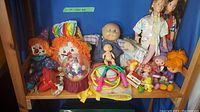 Photo showing assortment of vintage dolls including Cabbage Patch Kids, Care Bears, Strawberry Shortcake and Hot Looks, along with colorful toy clowns and assorted small plastic toys.