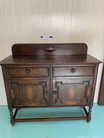 Front view of antique walnut buffet showing drawers and cupboards with carved panels and turned legs.