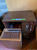 Antique wooden cabinet radio with tuning dials and speaker grill on front right, humidifier next to it.