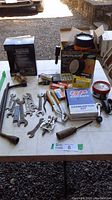 Overview of lot on table showing spotlight, spark plugs, wrenches, carburetor kit, knife, and other tools.