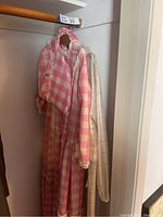 Photo of pink gingham dress, matching bonnet, and plastic raincoat hanging in closet